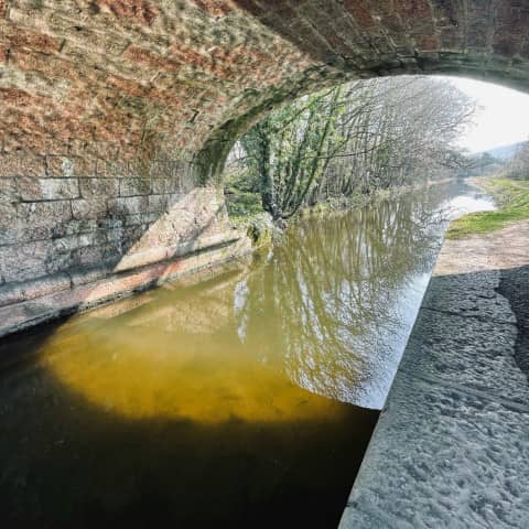 A canal flowing under an old brick and stone bridge.